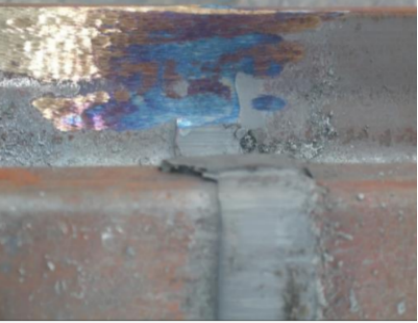 Grinding burn on a rail weld — the blue-black discoloration marks a thermally altered surface layer