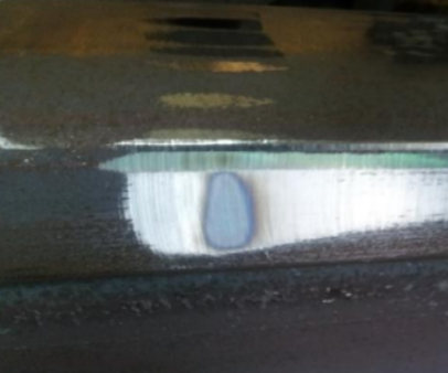 A blue burn spot left in the centre of a dressed weld area