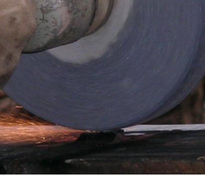 Hand-held grinding in progress — controlling pressure and dwell time is critical to avoiding burn